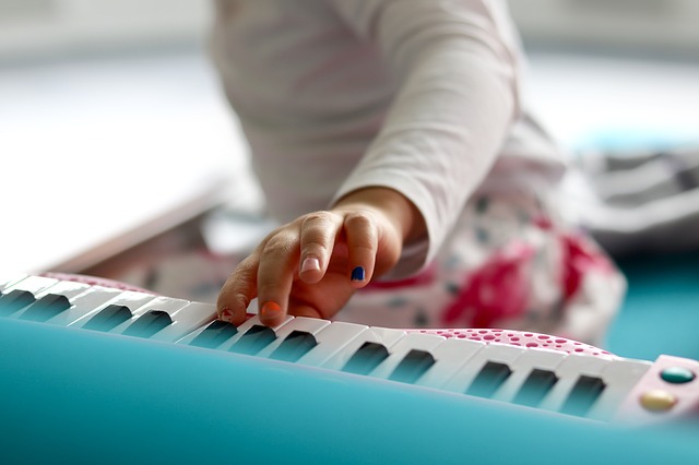Barnehånd med gyllenbrun farge som spiller på et keyboard. Nærbilde.